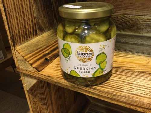 Jar of Biona Organic Gherkin Slices on a wooden shelf.