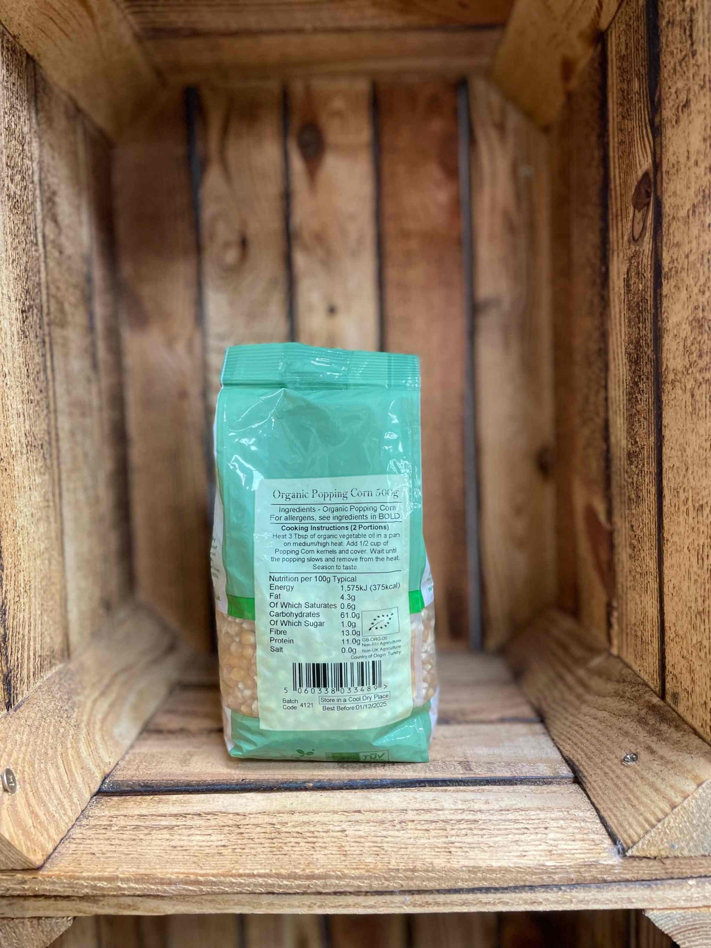 Organic Popping Corn 500g package on wooden shelf.