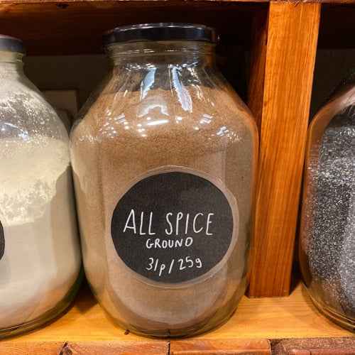 Jar of ground all spice labeled with price and weight, ideal for enhancing culinary dishes with aromatic flavors.