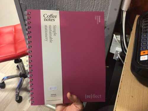 Grande Notebook Plain with brown hardcover and spiral binding displayed vertically in a hand.