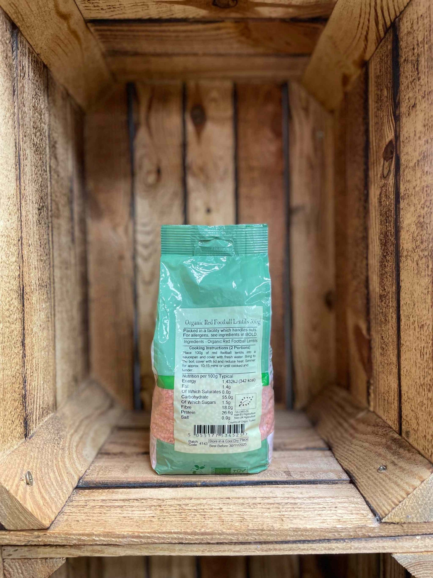 Organic Red Football Lentils packaging displayed on a wooden shelf.