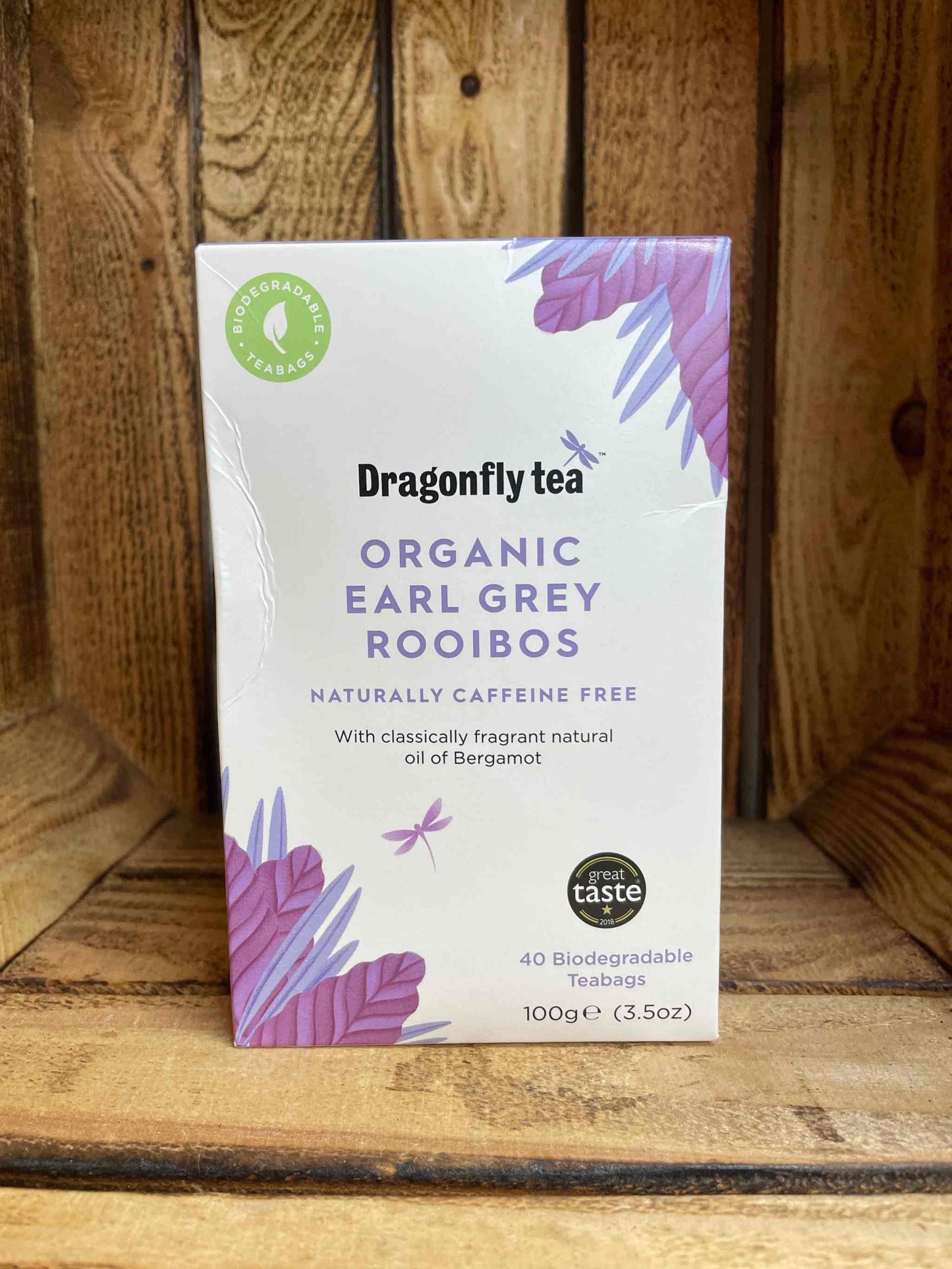 Organic Earl Grey Rooibos tea box on wooden background, featuring natural bergamot oil and caffeine-free.