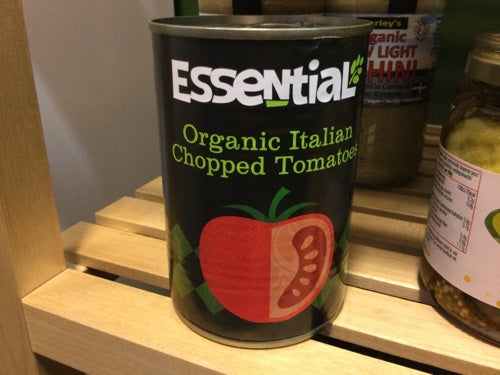 Organic chopped tomatoes can on a wooden shelf.