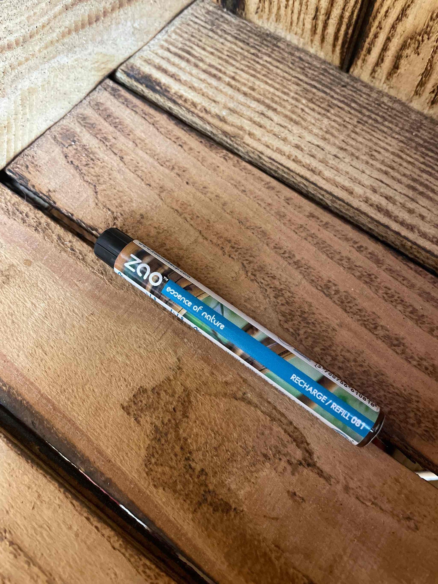 Eco-friendly mascara refill on wooden surface.