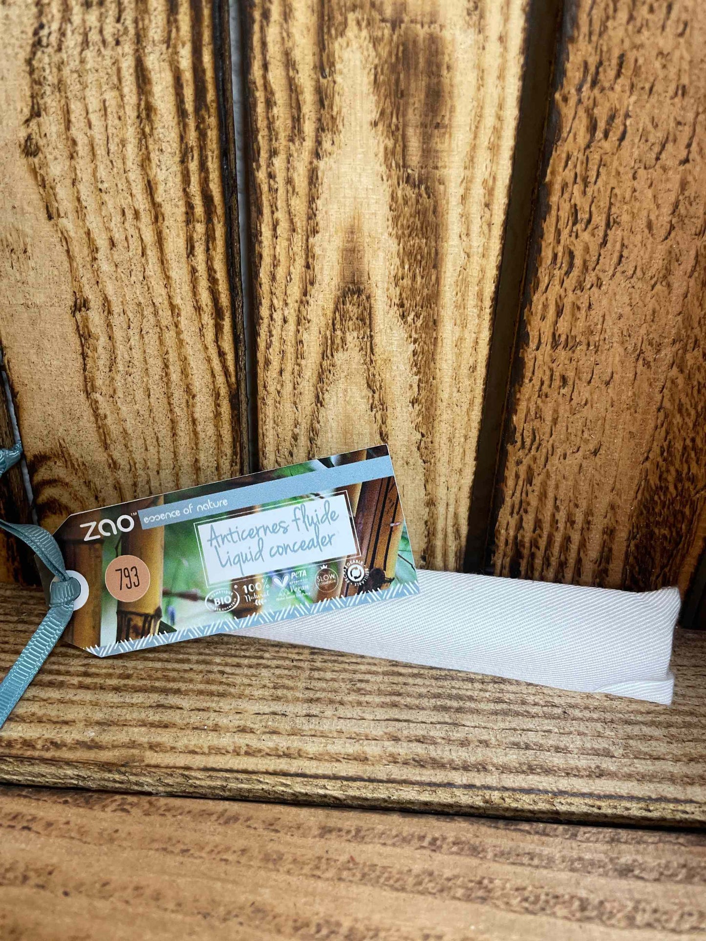 Liquid concealer with seamless coverage and nourishing ingredients on a wooden background.