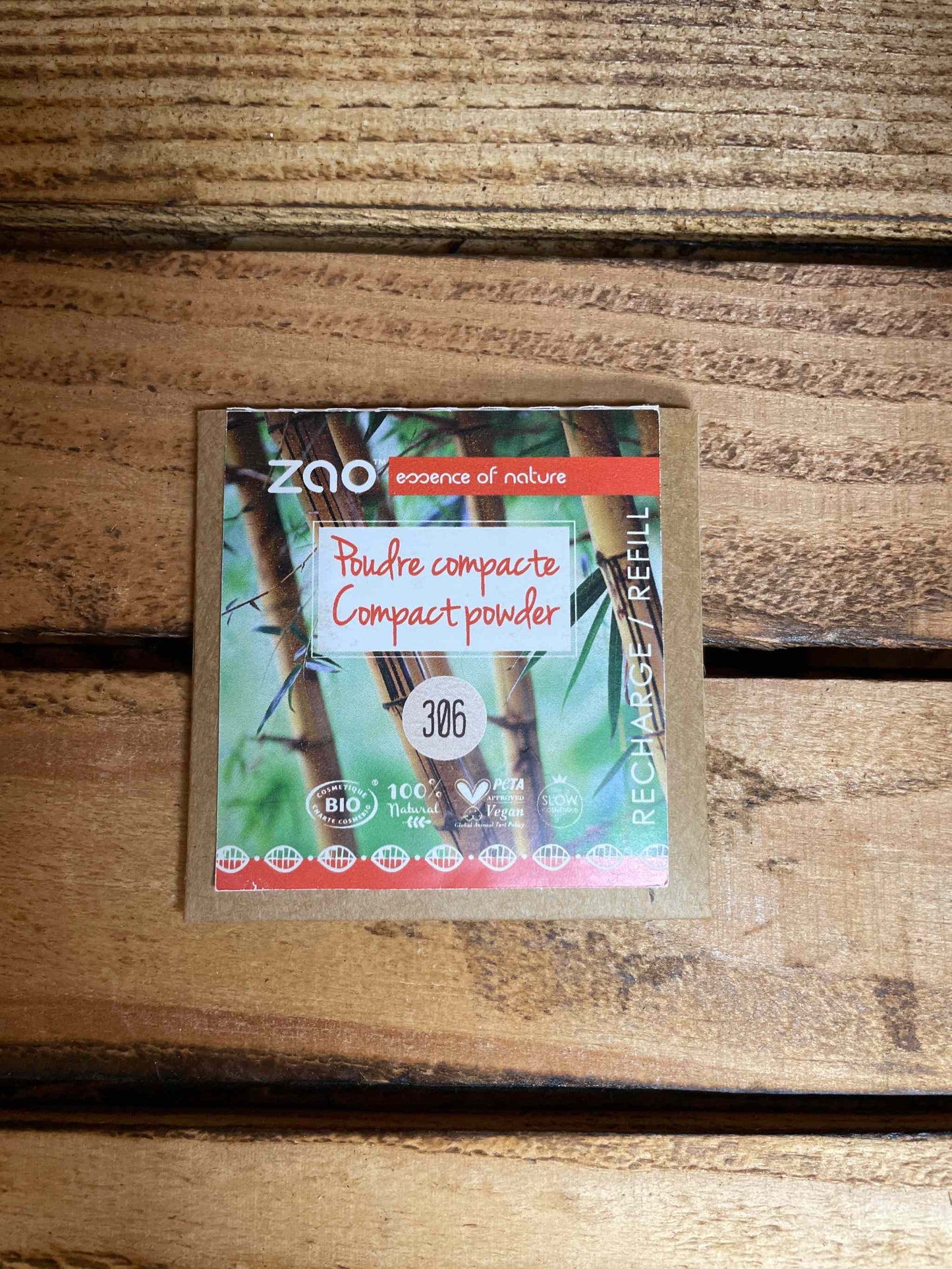 Compact Powder Refill on wooden surface, eco-friendly packaging featuring bamboo designs.
