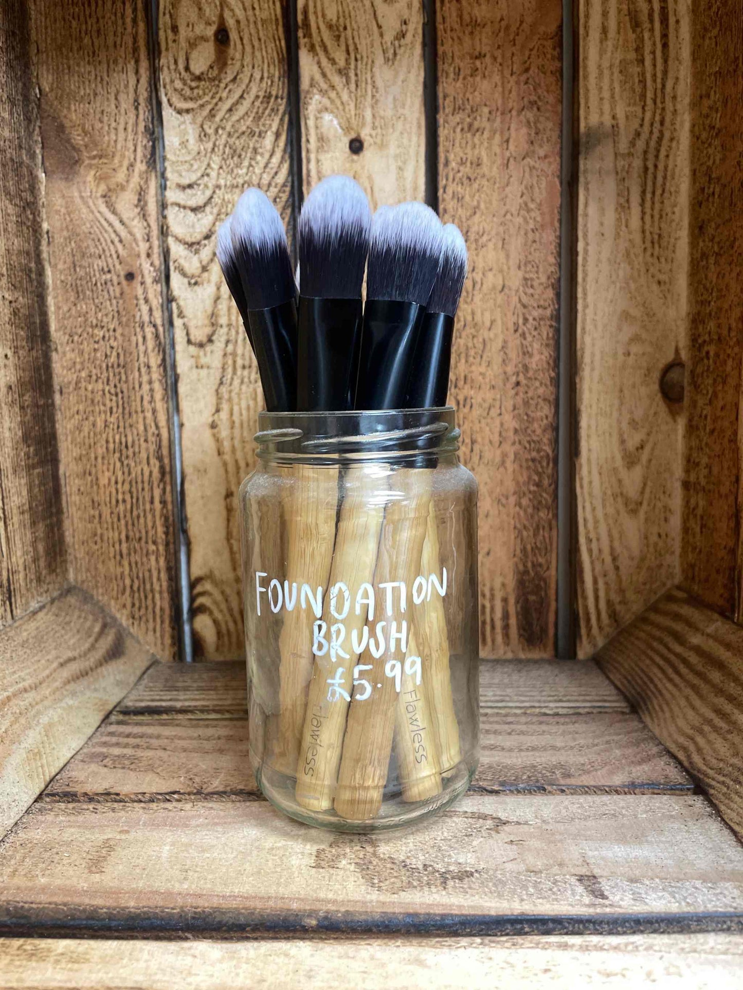 Premium foundation makeup brushes in a jar against a wooden background.