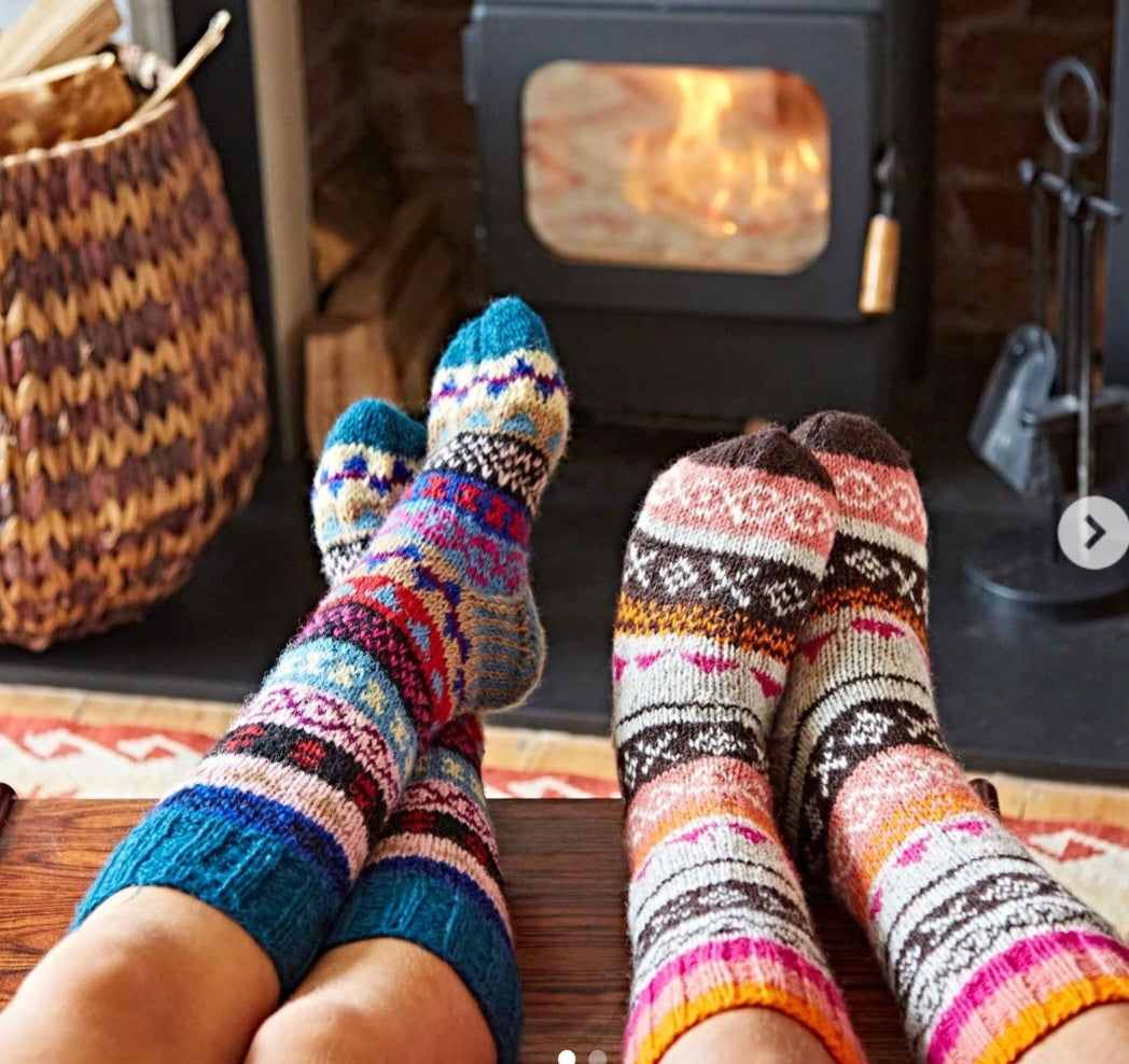 Cozy woolen long socks in colorful patterns by a fireplace.