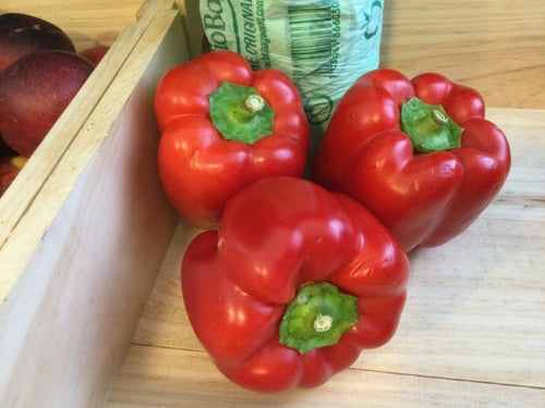 Organic red peppers on wooden surface with vibrant color and fresh appearance.
