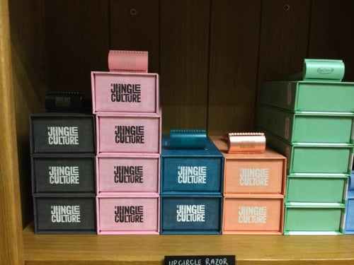 Jungle Culture razors displayed in various colored boxes on a wooden shelf.