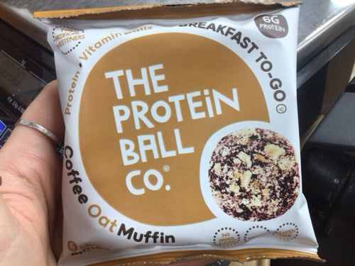 Protein ball Coffee and Oat Muffin packaging with hand holding the product.