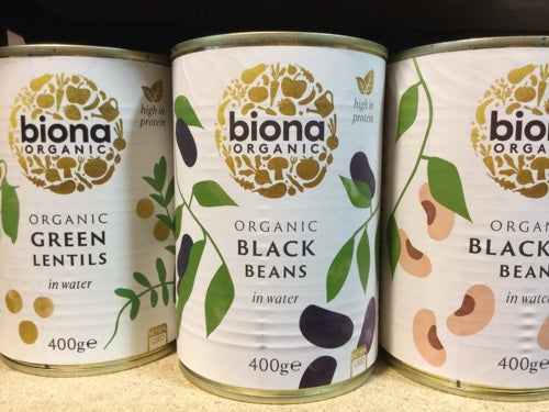 Biona black eye beans organic cans on a shelf displaying organic label and high protein content.