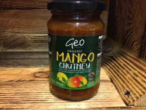 Jar of Geo Organic Mango Chutney on wooden surface.