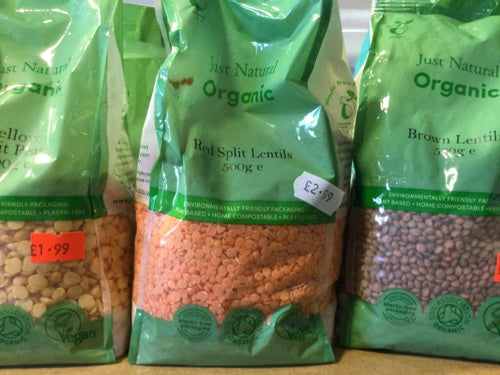 Organic red split lentils in green packaging on a store shelf.