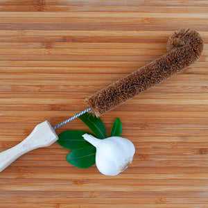Eco-friendly bottle brush made from coconut fibers on a wooden surface.