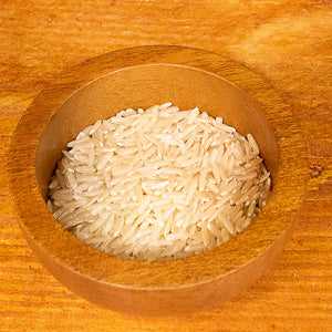 Brown jasmine rice (100g) in a wooden bowl on a wooden surface.