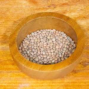 Brown lentils (100g) in a wooden bowl, showcasing their rich, earthy texture.