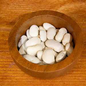 Butter beans in a wooden bowl on a wooden surface, 100g.