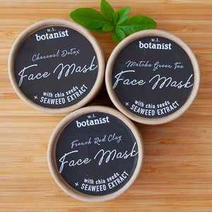 White Label Botanist face masks with charcoal detox, matcha green tea, and French red clay varieties on a wooden surface.