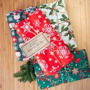 Small reusable gift bags with festive designs in red, green, and white colors, ideal for sustainable gifting.
