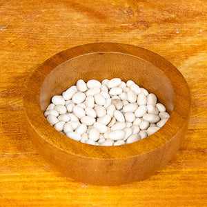 Haricot beans in a wooden bowl on a wooden surface.