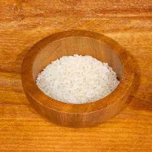 Jasmine rice in a wooden bowl on a wooden surface.