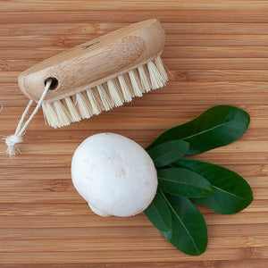 Eco-friendly nail brush by Croll & Denecke with soft natural bristles and biodegradable wooden handle on wooden surface.