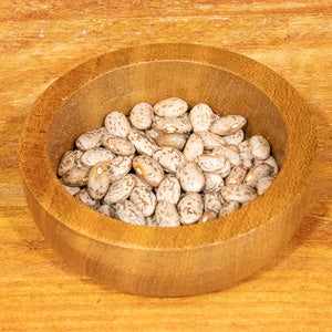 Pinto beans in a wooden bowl on a wooden surface, 100g.