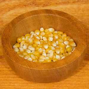 Popping corn kernels in a wooden bowl, 100g package.