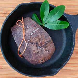 Eco-friendly washing-up scraper by LoofCo made from natural coconut fibers in a cast iron pan.