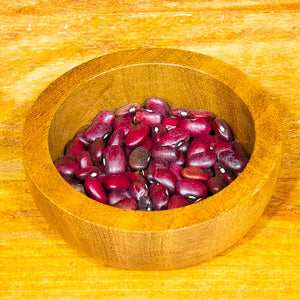 Red kidney beans in wooden bowl on wooden surface.