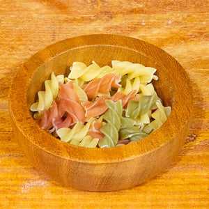 Tricolore pasta, organic, 100g, colorful fusilli in wooden bowl.