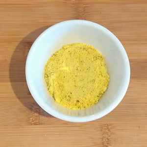 Vegan bouillon powder in a white bowl on a wooden surface.
