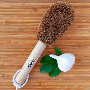 Eco-friendly LoofCo washing-up brush made from natural coconut fibers on a wooden board.