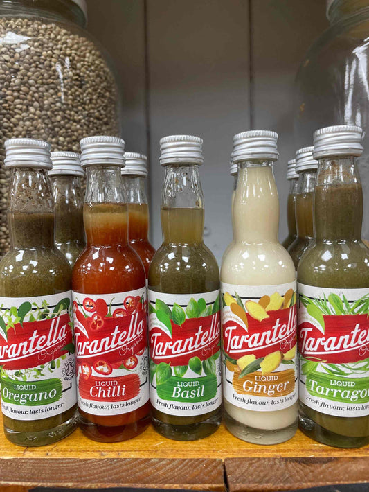 Tarantella Organic Liquid Herbs bottles on a shelf, featuring a variety of flavors including basil.