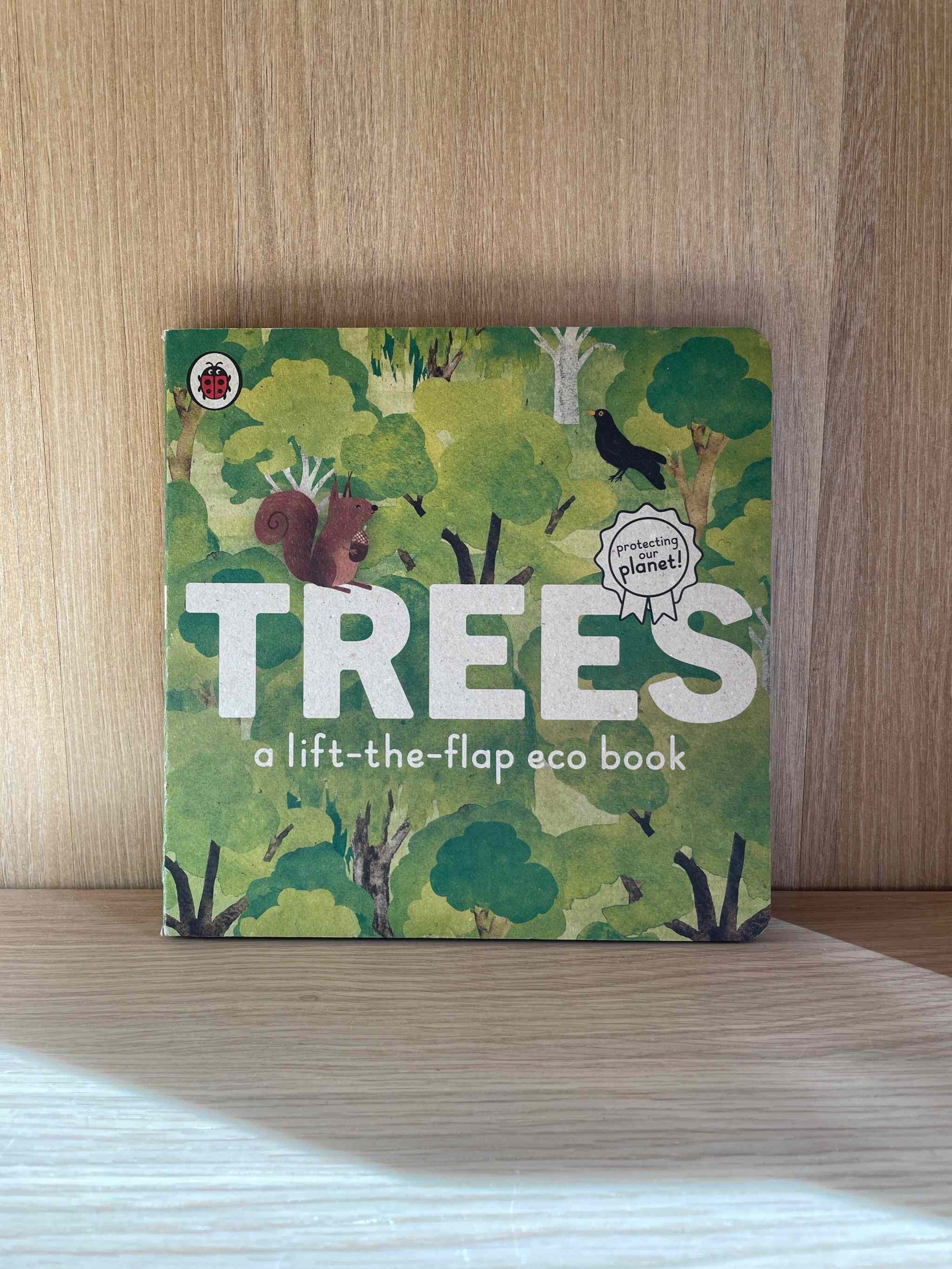 Trees Eco Book on a wooden surface with forest illustration and eco-friendly theme.