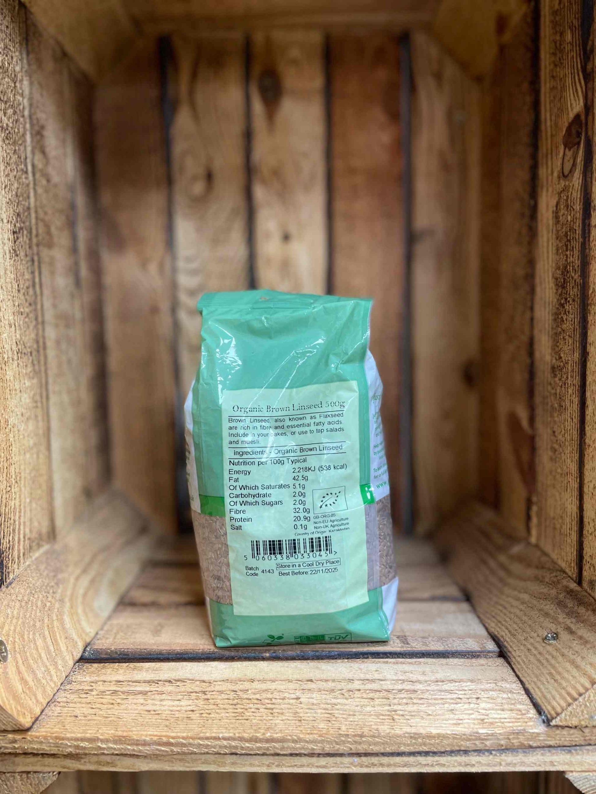 Organic brown linseed 500g package on wooden shelf.