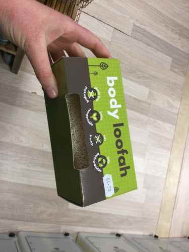 Eco-friendly Body Loofah packaging on wooden floor, promotes natural exfoliation and sustainable living.