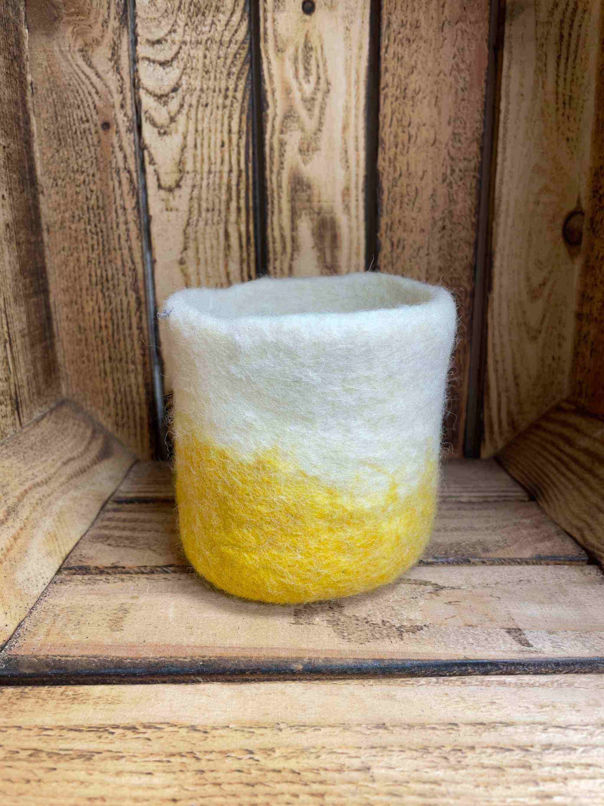 Yellow felt handmade jute small container on wooden background; eco-friendly home decor.