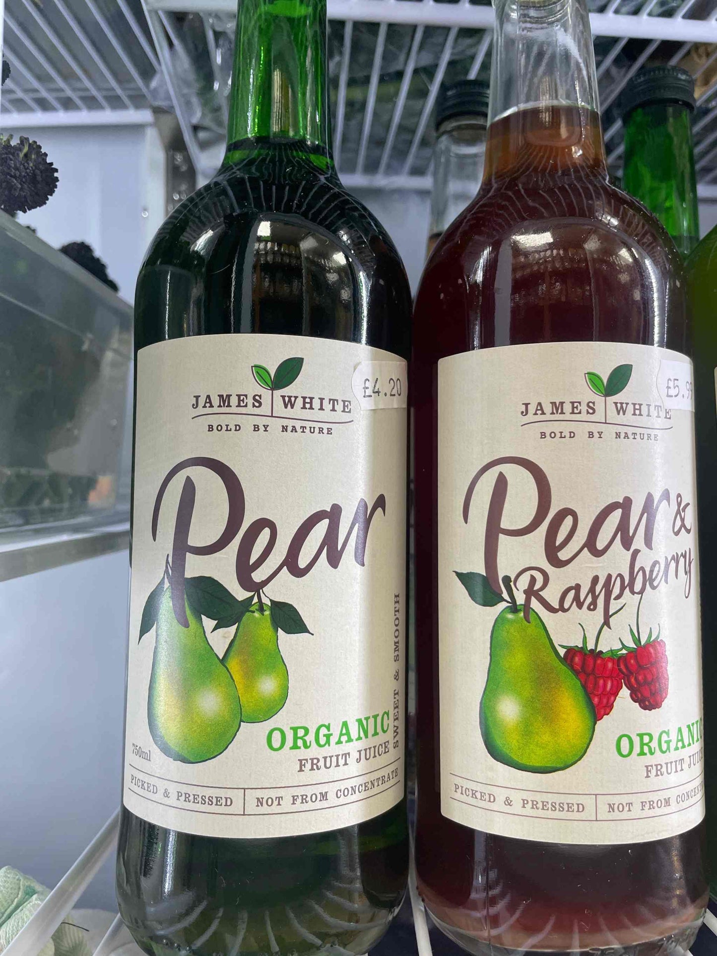 James White Juice Pear bottles on display in a refrigerator, showcasing organic fruit juice options.