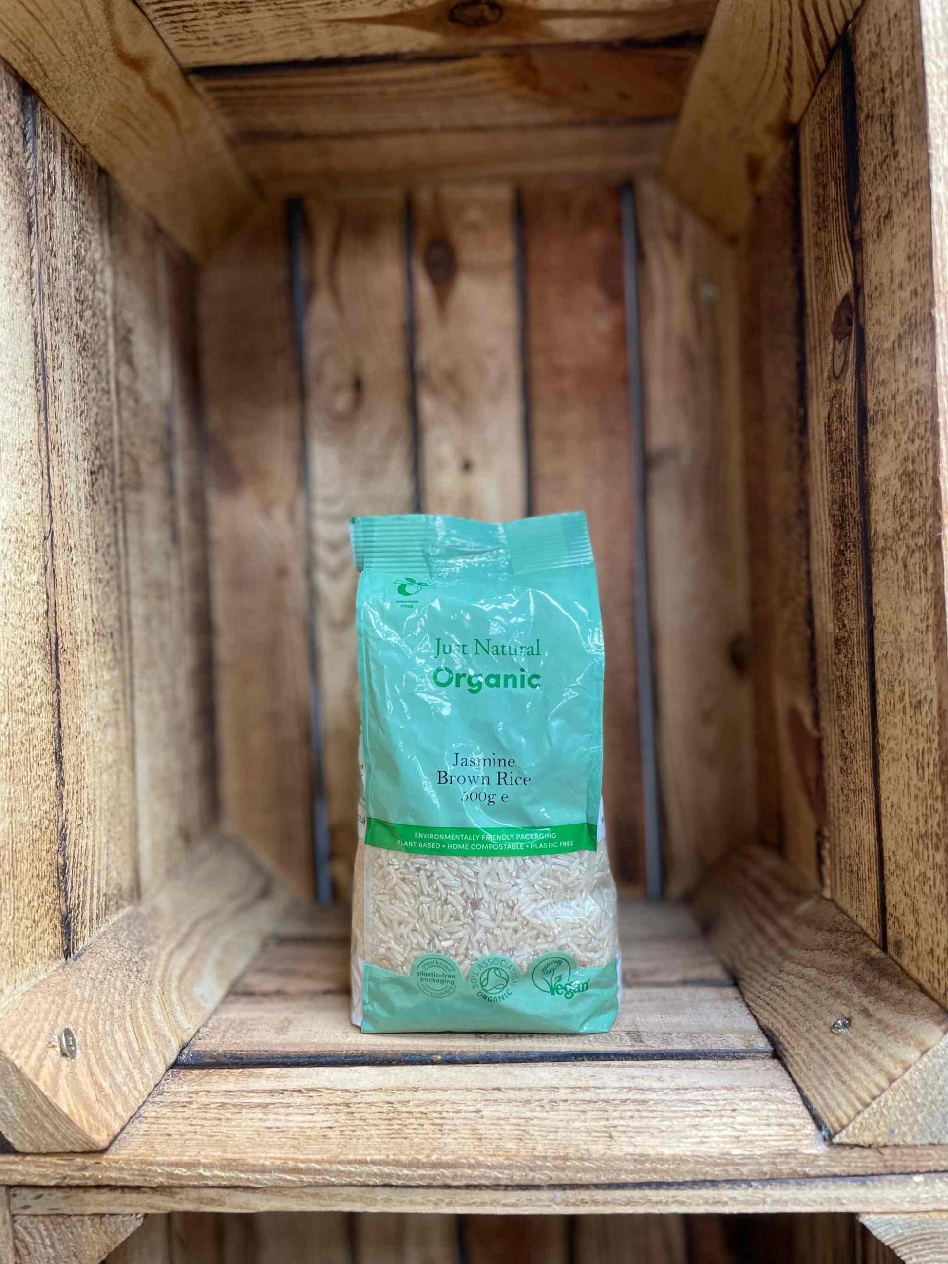 Organic Brown Jasmine Rice 500g in eco-friendly packaging on wooden shelf.