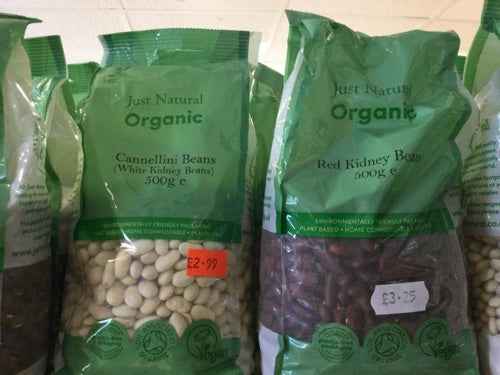 Organic kidney beans packaged in green bags, labeled as "Just Natural Organic," on display for sale.