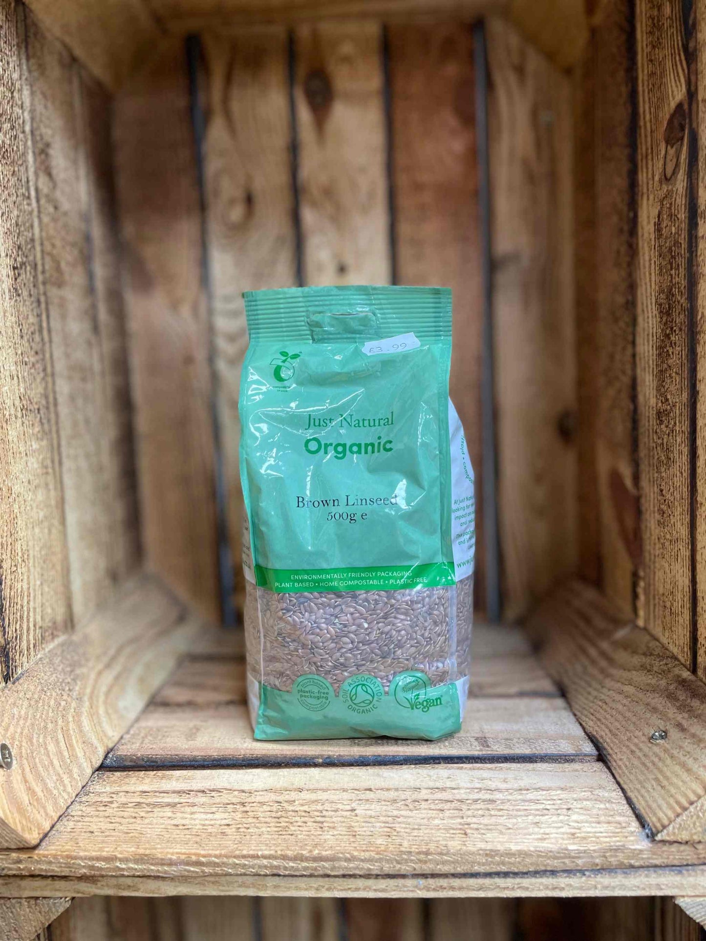 Organic brown linseed 500g package on wooden shelf.