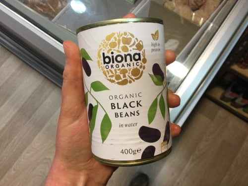 Organic black beans can in a hand, featuring Biona brand label.