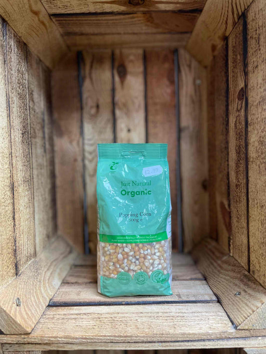 Organic Popping Corn 500g in a green bag, nestled in a wooden crate, premium and natural popcorn.