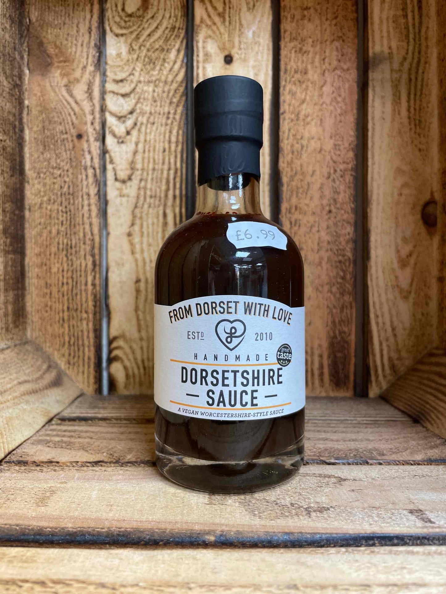 Bottle of Dorsetshire Sauce on wooden shelf, labeled as handmade and priced.