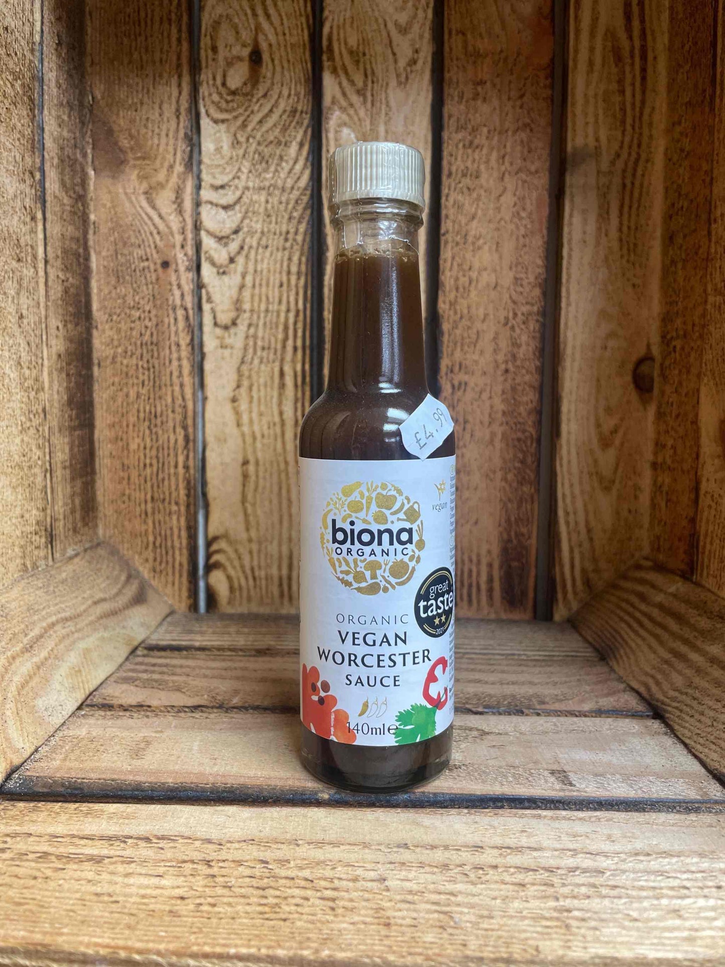 Bottle of organic vegan Worcester sauce with rich, savory flavor on a wooden surface.