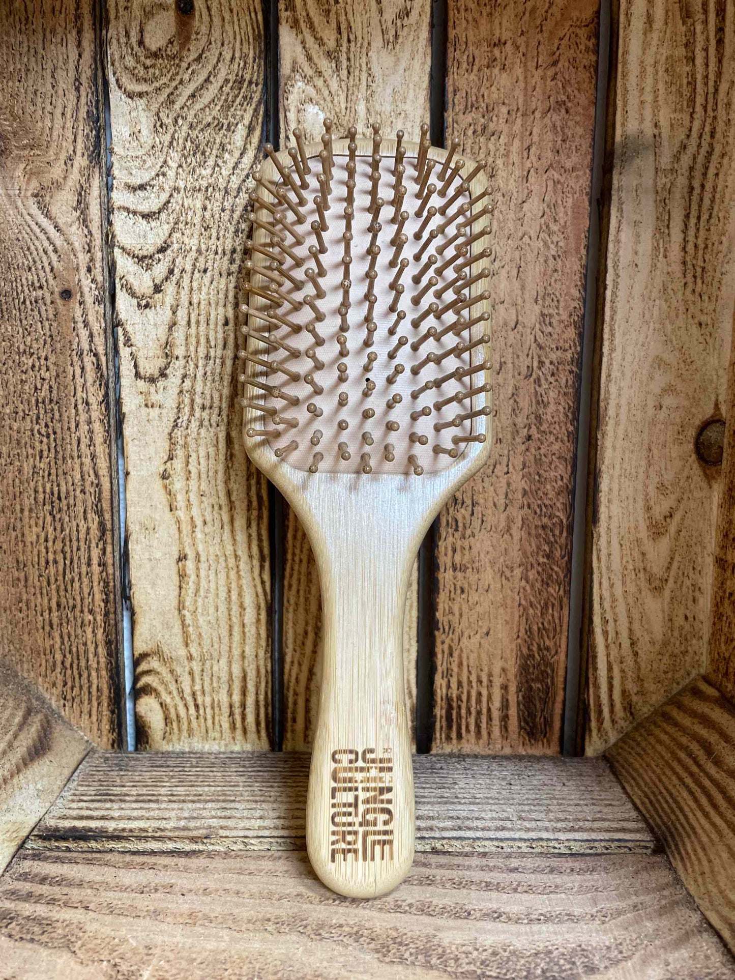 Bamboo hairbrush with natural bristles by Jungle Culture on wooden background.