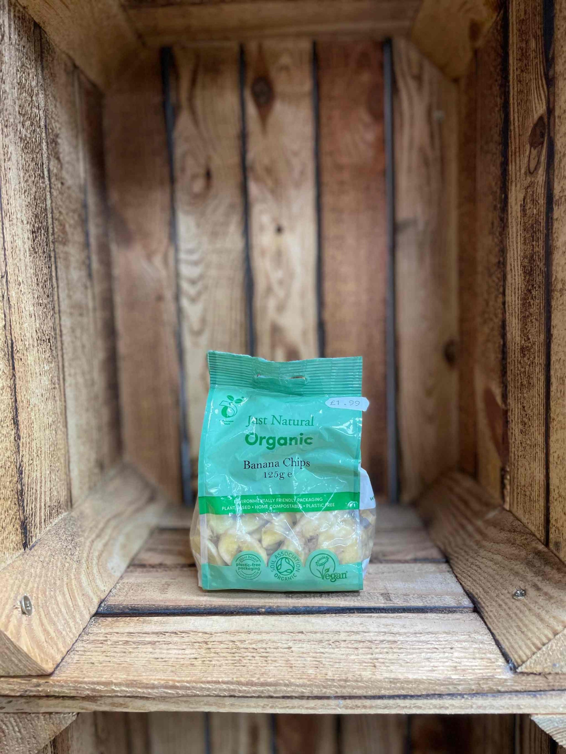 Organic banana chips in eco-friendly packaging displayed on a wooden shelf.