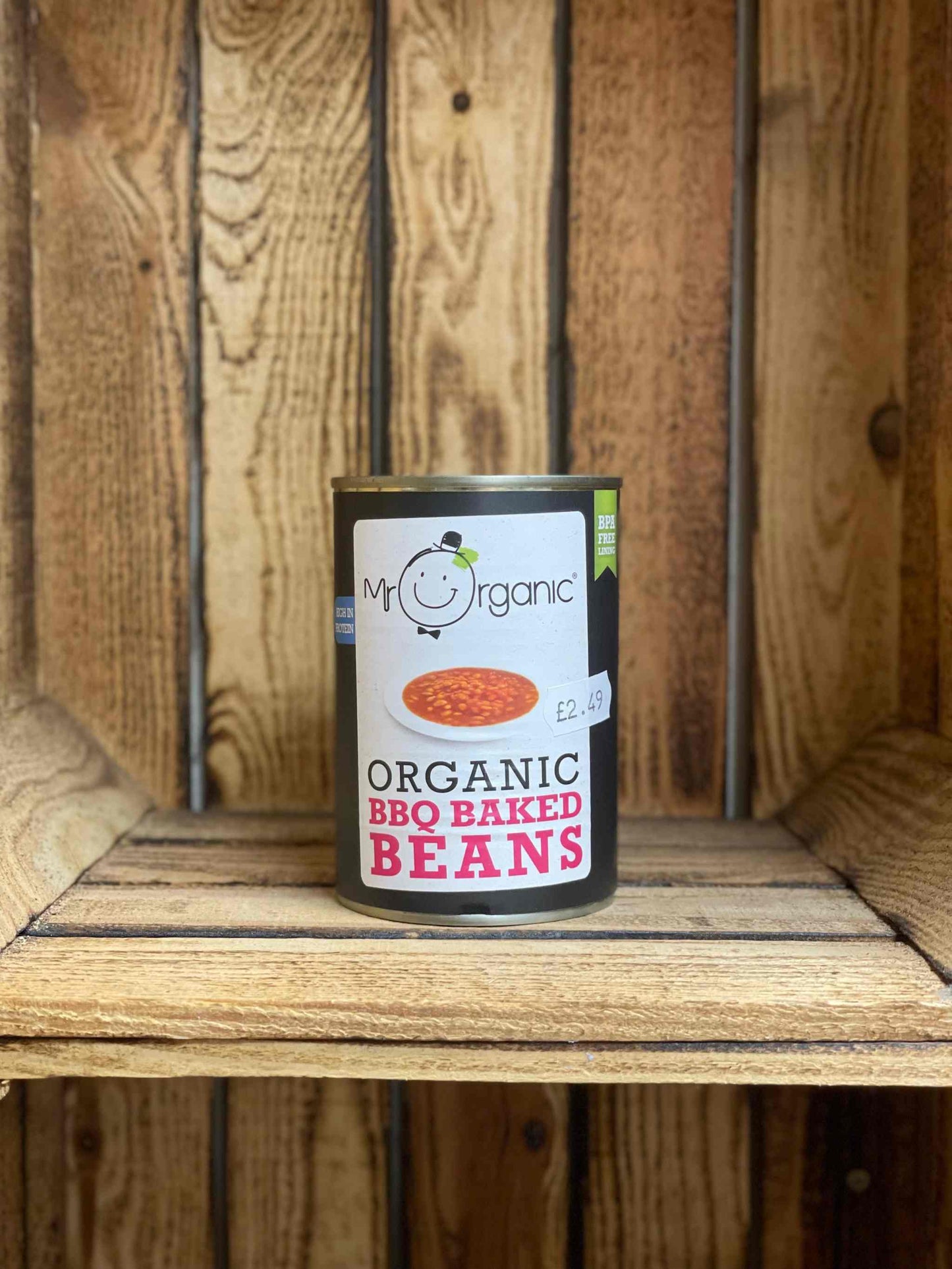 Organic BBQ baked beans can on rustic wooden shelf.